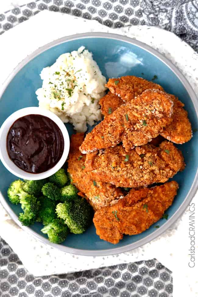 A blue plate covered in mashed potatoes, oven fried chicken, and broccoli.