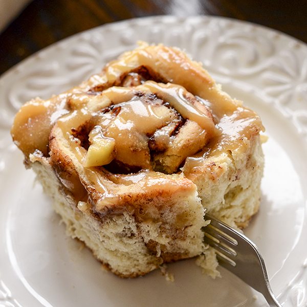 Angled view of caramel apple cinnamon roll on a plate.