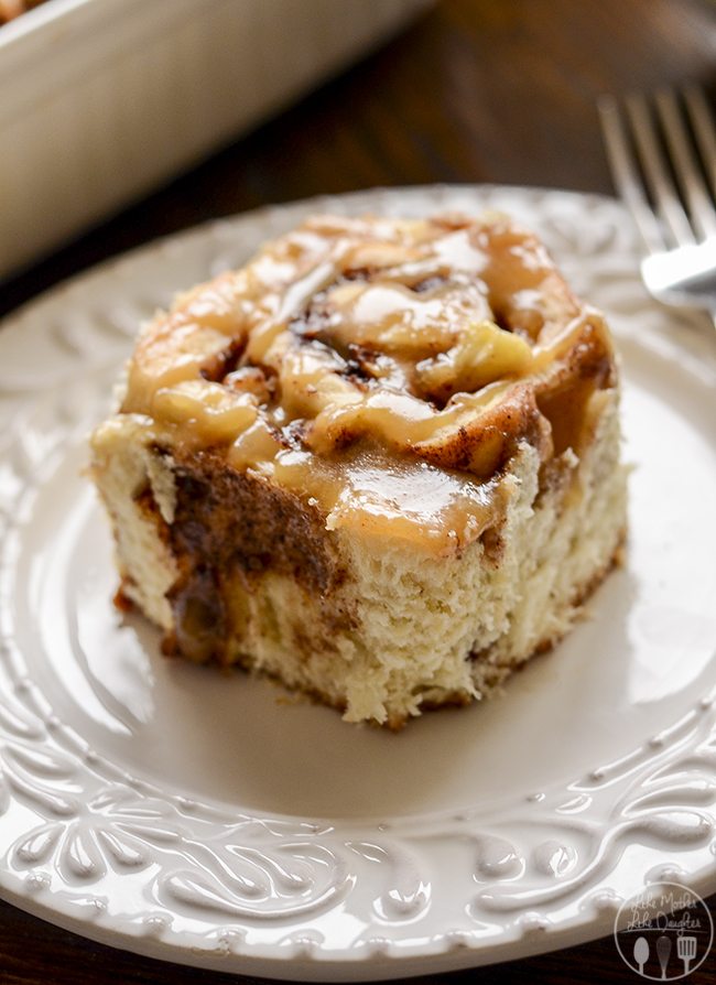 Angled view of caramel apple cinnamon roll on a plate with fork.