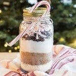 Side view of a hot chocolate mix in a jar with a candy cane.