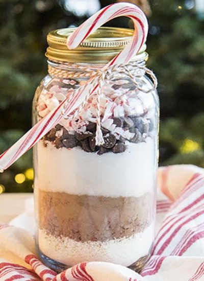 Side view of a hot chocolate mix in a jar with a candy cane.