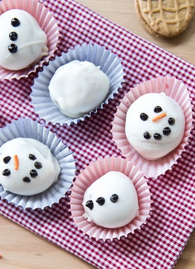 Above view of nutter butter snowman truffles on a plaid cloth.