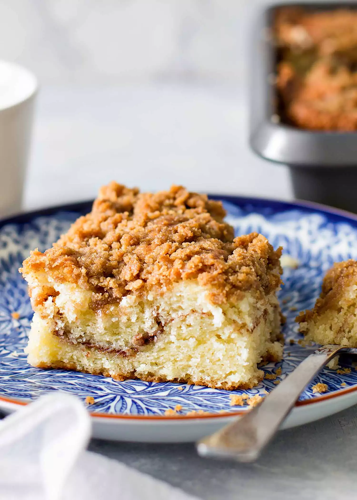 A slice of coffee cake with a cinnamon swirl in the middle on a blue plate. 