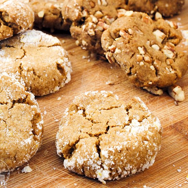 Angled view of orange molasses cookies on a white board.