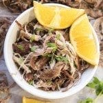 Above view of slow cooker pork carnitas in a mug with orange slices.