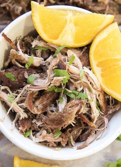 Above view of slow cooker pork carnitas in a mug with orange slices.