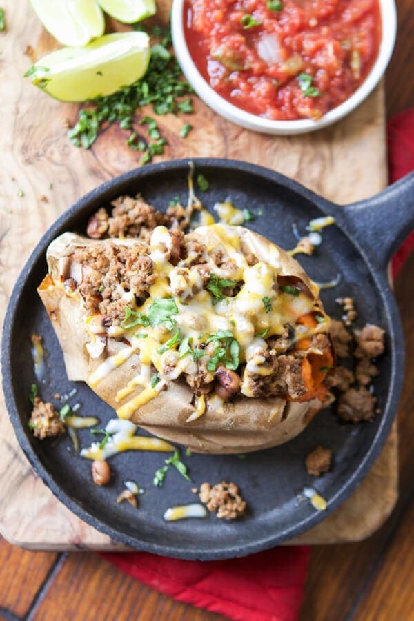 A sweet potato stuffed with ground beef, and topped with melted cheese on a plate.