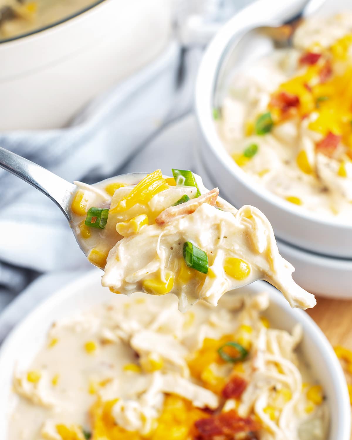 A spoonful of chicken and corn chowder above a bowl of it.