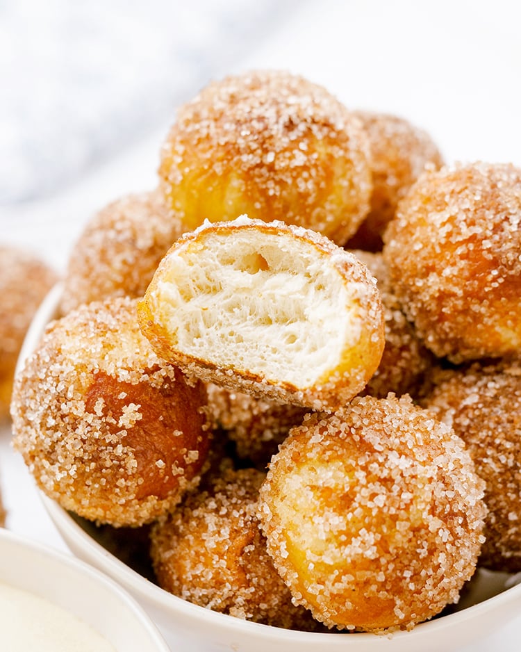 A close up of cinnamon sugar soft pretzel bites. One is bit open showing the soft bread in the middle.