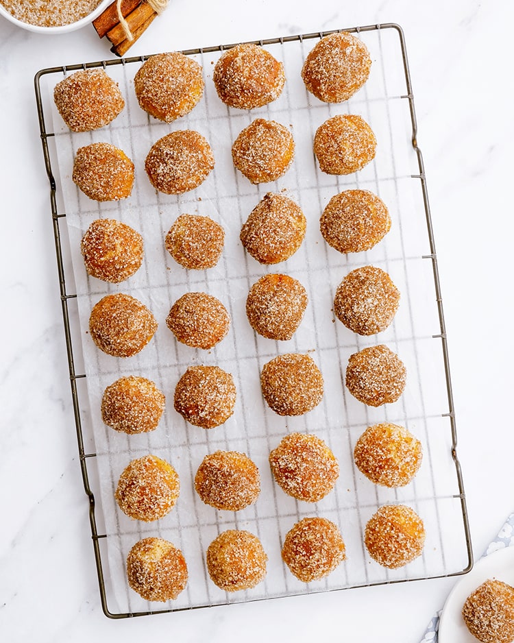A cooling rack full of cinnamon sugar soft pretzel balls laid out in rows.