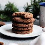 A stack of Mexican hot chocolate snickerdoodles on a plate, and the top cookie has a bite out of it.