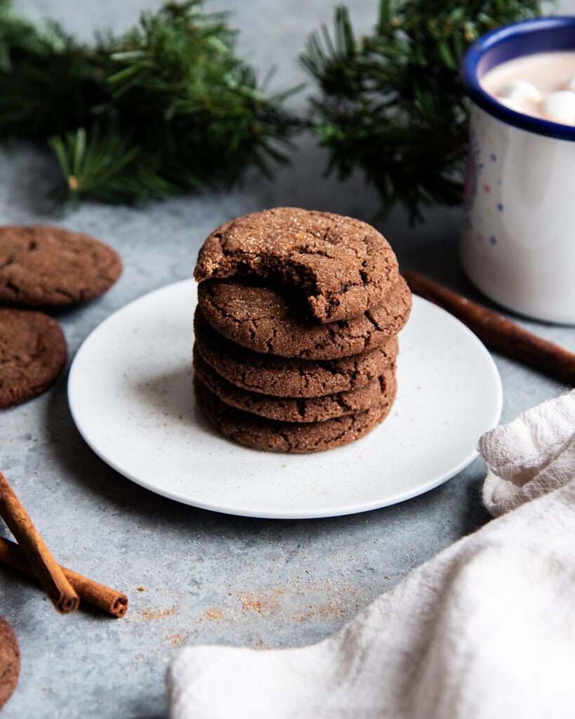 A stack of Mexican hot chocolate snickerdoodles on a plate, and the top cookie has a bite out of it.