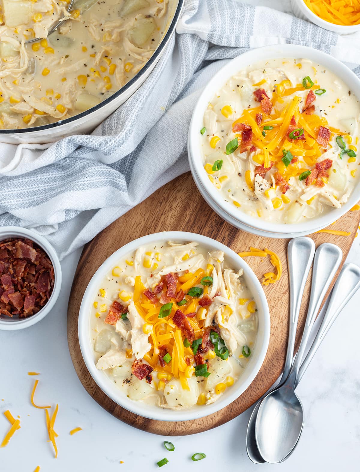 An overhead photo of two bowls of chicken chowder, each topped with shredded cheese, and bacon pieces.