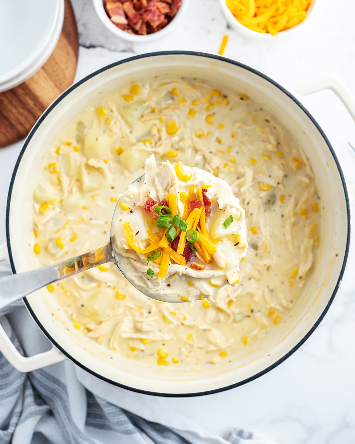 An overhead photo of a pot of cheesy chicken chowder with a ladle of it above the pot.