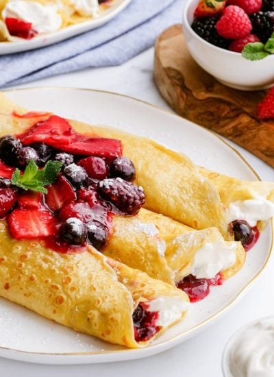 A close up of three rolled crepes full of a cheesecake filling, and macerated berries!