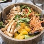 Angled image of oriental chicken salad in a wooden bowl.
