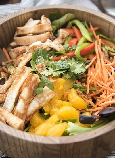Angled image of oriental chicken salad in a wooden bowl.