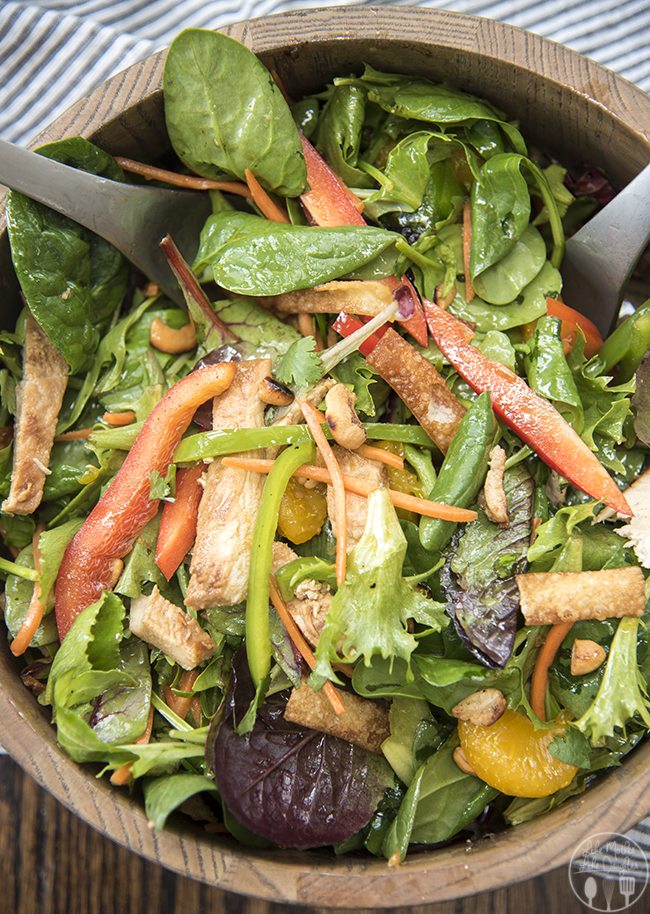 Close up image of oriental chicken salad in a wooden bowl.
