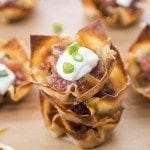 Close up photo of wonton taco cups with sour cream on top.