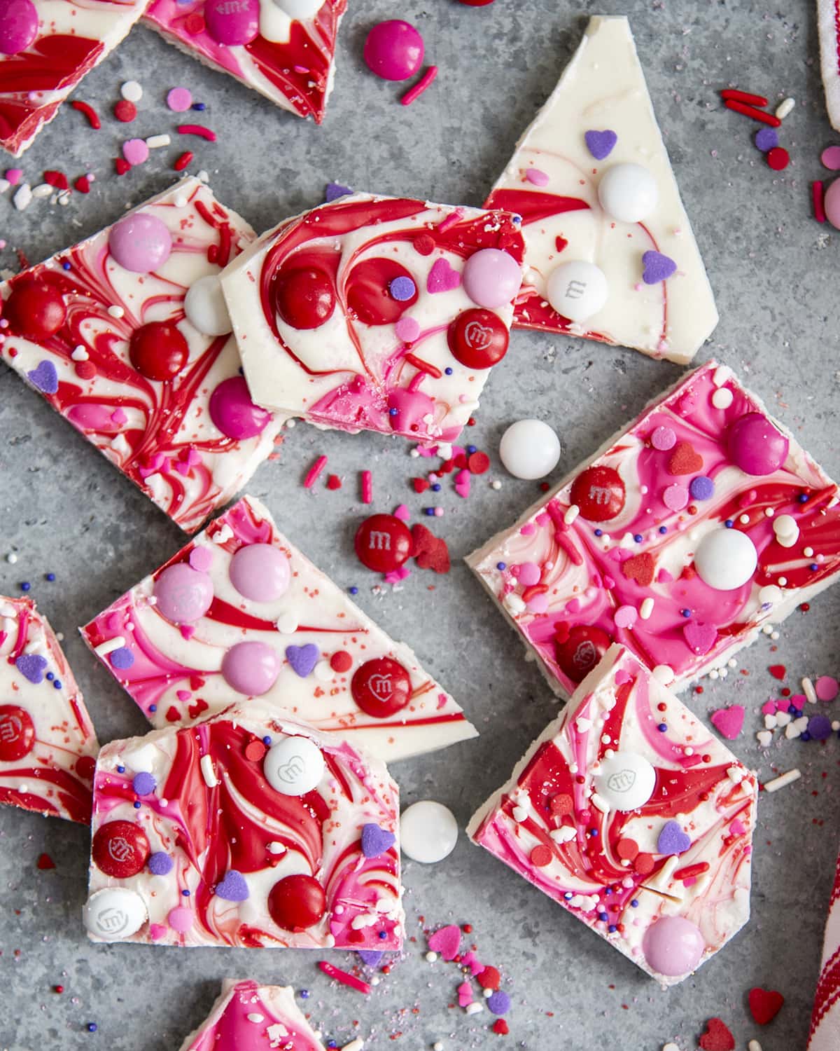 An overhead photo of pieces of Valentine's Day white chocolate bark overlapped on a countertop.