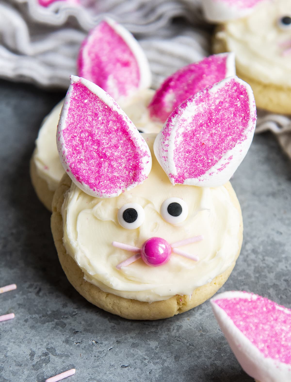 An Easter Bunny Cookie decorated with white frosting, marshmallows, candy eyes, and a pink candy nose.