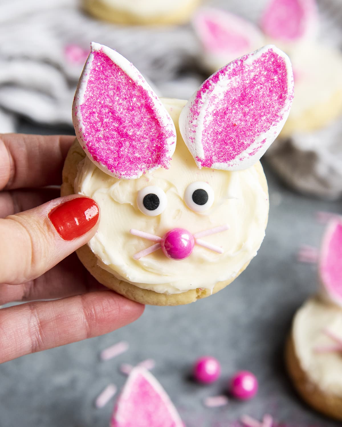 A hand holding a cookie decorated like a cute bunny.