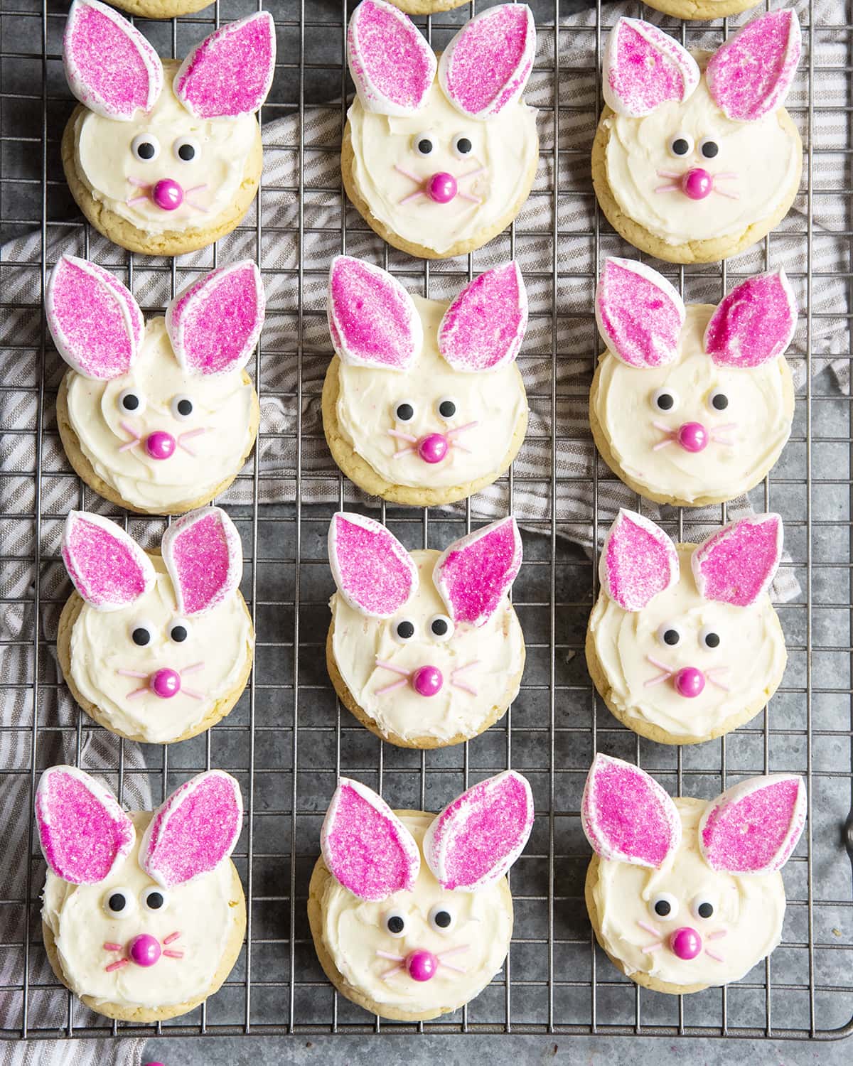 A cooling rack topped with rows of cute bunny face cookies.
