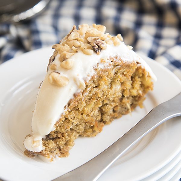 Angled image of a slice of lighter carrot cake on a white plate.