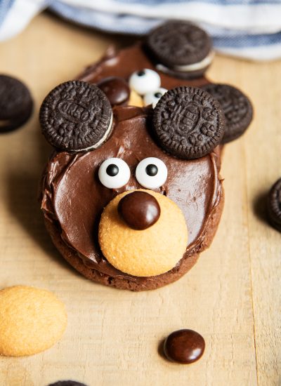 A bear Cookie decorated with chocolate frosting, and a cookie nose, candy eyes, and two Oreo eyes.