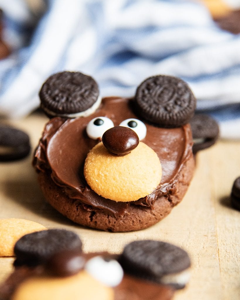 A chocolate cookie decorated to look like a bear with candy eyes and mini Oreo ears.