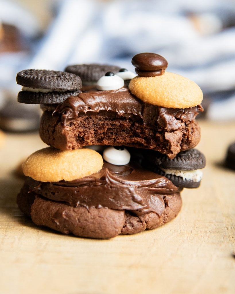 A stack of two chocolate bear cookies, and the top cookie has a bite out of it.