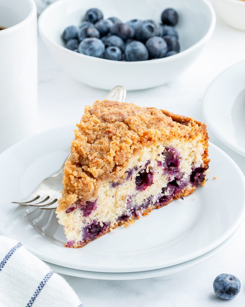 A piece of blueberry coffee cake on a white plate.