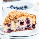 A slice of blueberry coffee cake full of big blueberries, and topped with a streusel crumb topping.
