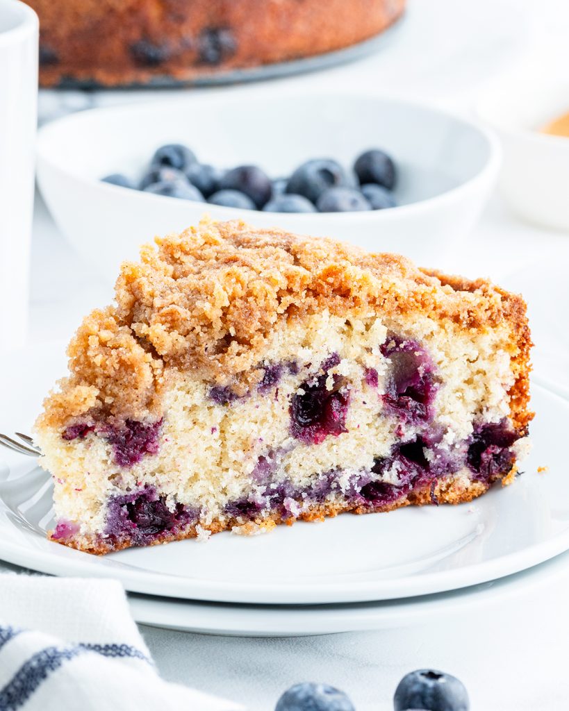 A slice of blueberry coffee cake full of big blueberries, and topped with a streusel crumb topping.