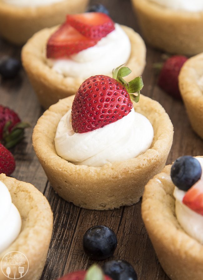 Side image of lemon poke cake with strawberry and mint on top on a white plate.