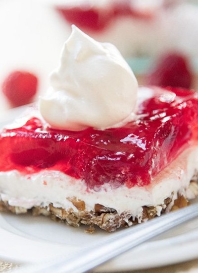Side image of raspberry pretzel jello salad on a white plate.