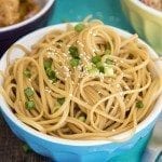 Close up image of sesame noodles in a blue and white bowl.