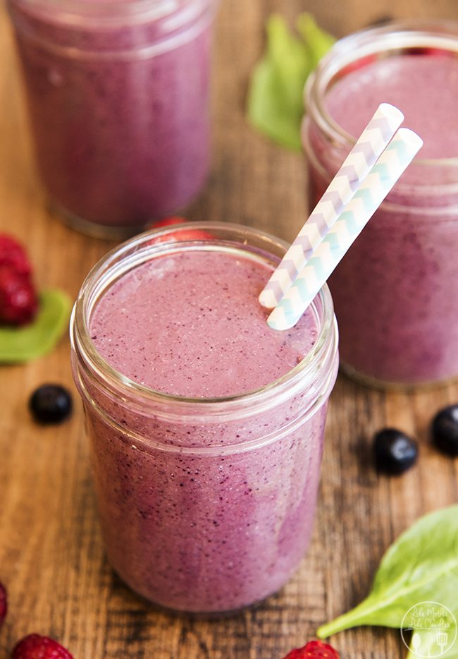 Angled image of a glass of triple berry green smoothie.