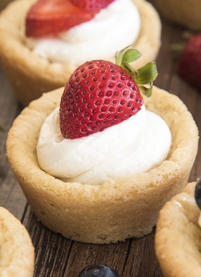 Side image of lemon poke cake with strawberry and mint on top on a white plate.