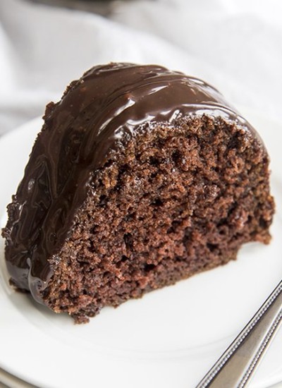 Side image of chocolate bundt cake on a white plate with a fork.