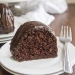 Side image of chocolate bundt cake on a white plate with a fork.