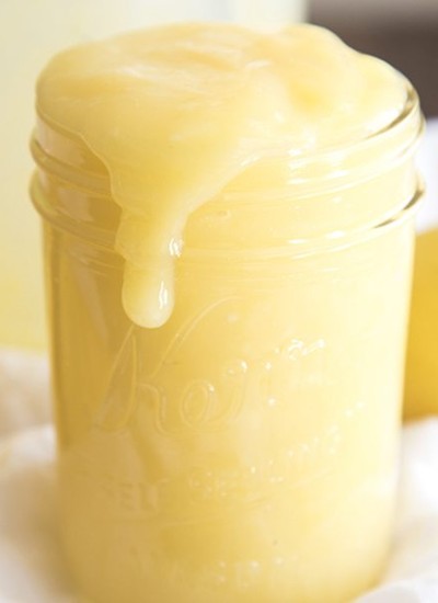 Side image of lemon curd pouring over a mason jar.