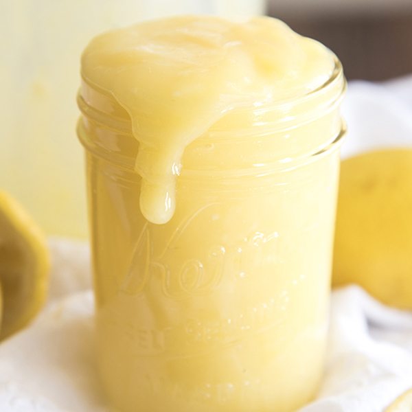 Side image of lemon curd pouring over a mason jar.