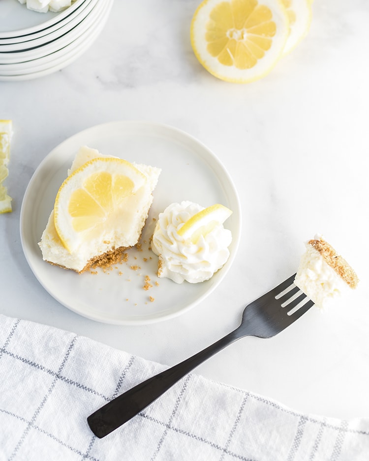 A bite taken out of a lemon cheesecake bar on a plate