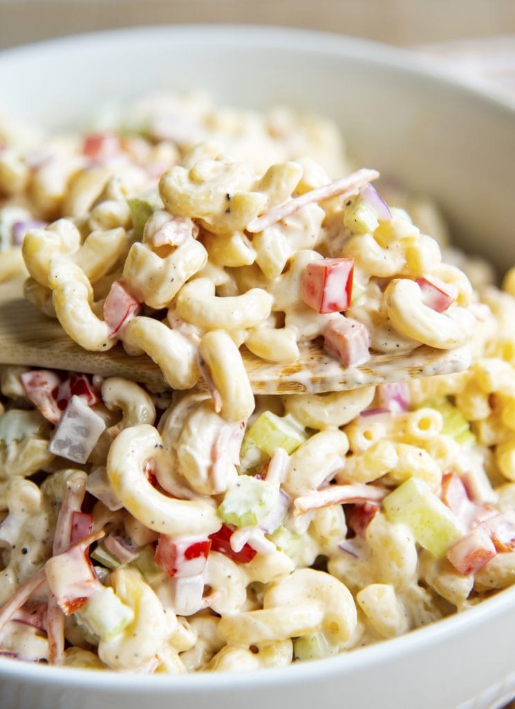 A large spoonful of macaroni salad just out of the bowl of the creamy salad.