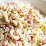 A large spoonful of macaroni salad just out of the bowl of the creamy salad.