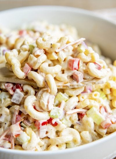 A large spoonful of macaroni salad just out of the bowl of the creamy salad.