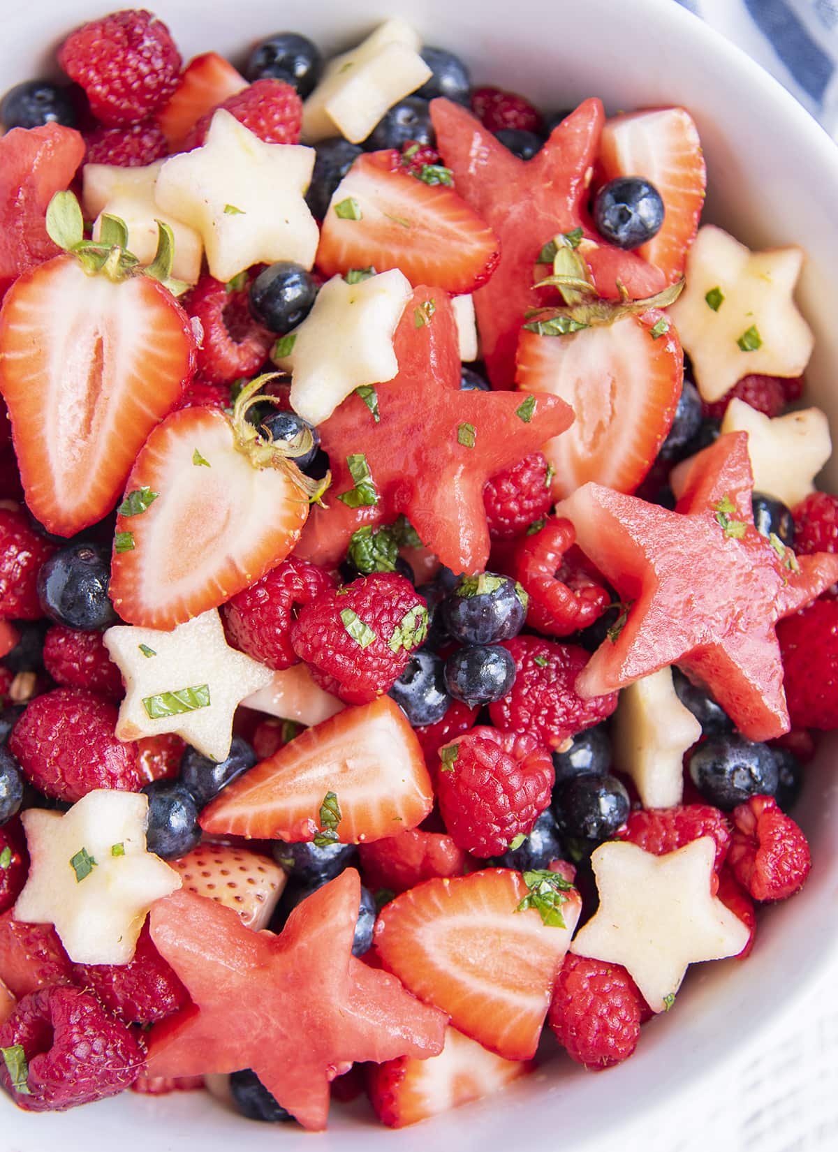 A bowl of red, white, and blue fruit salad with apple, and watermelon stars.