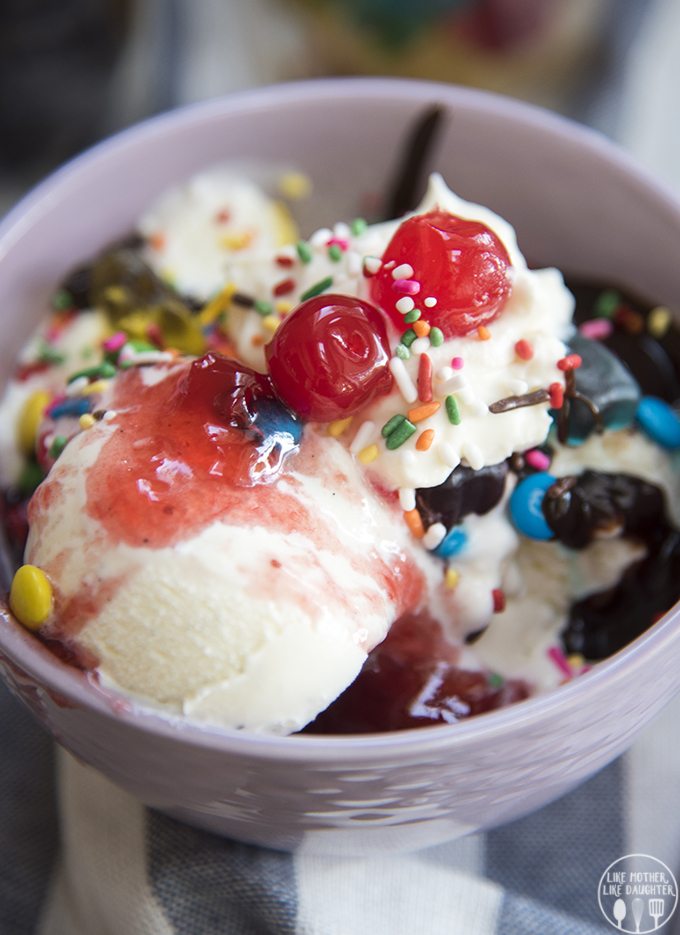 Close up image of a banana split bar in a bowl topped with sprinkles and cherries.