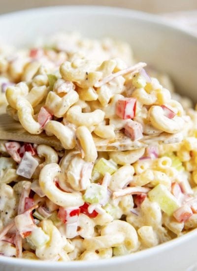 A large spoonful of macaroni salad just out of the bowl of the creamy salad.